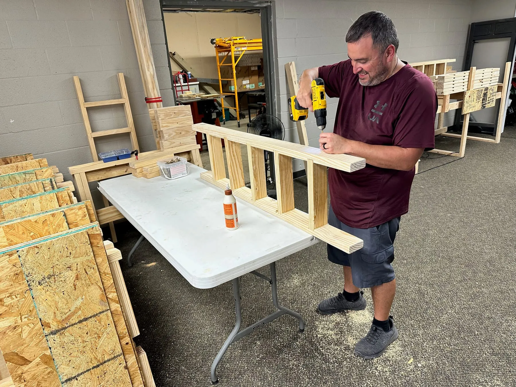 A volunteer drilling a wooden bed component