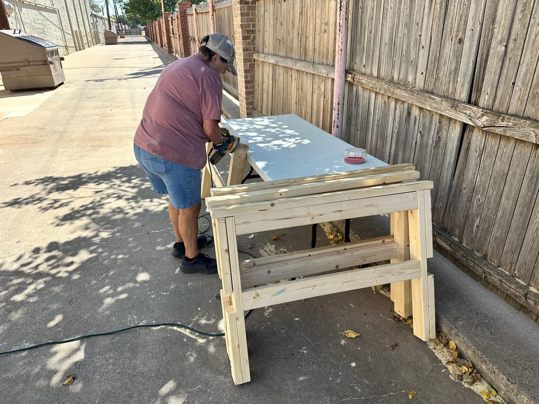 A volunteer sanding wooden bed parts outdoors